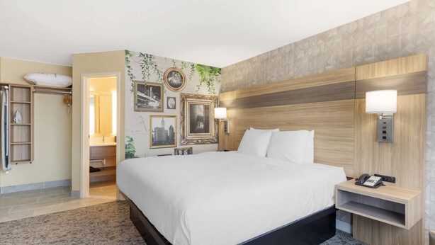 A hotel room with a large bed, a bedside table with a lamp, a wall-mounted phone, and a built-in shelf.