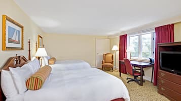 A hotel room with a large bed, two bedside tables, a desk, a chair, a television, and a window with curtains.
