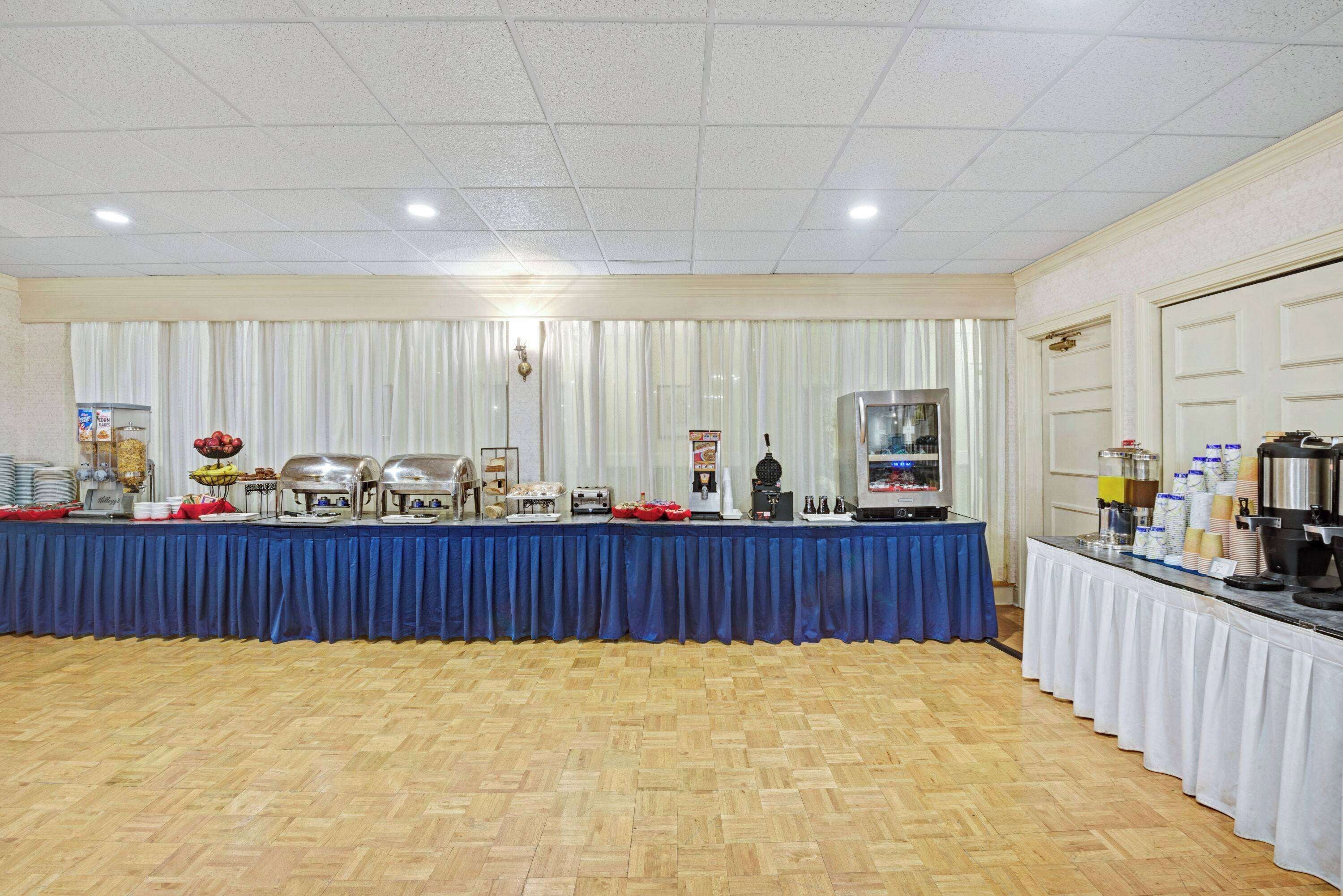 A buffet setup with a blue tablecloth, food service equipment, and a beverage station.
