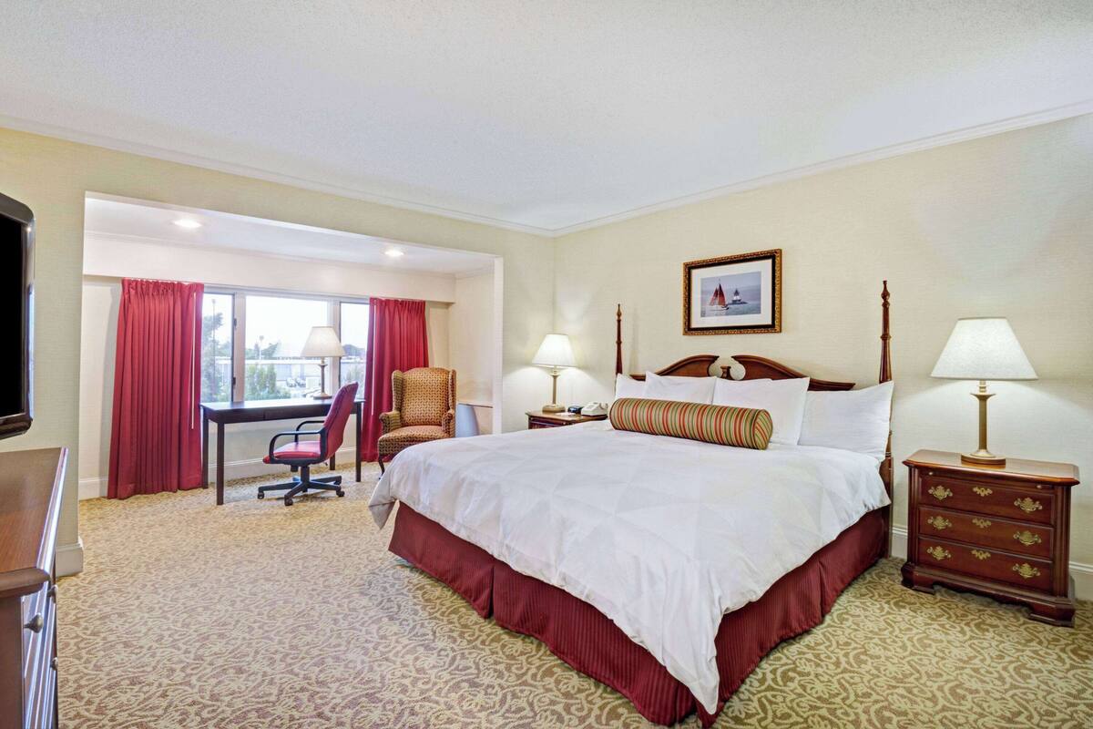 Een hotelkamer met een groot bed, een bureau, een stoel en een televisie.