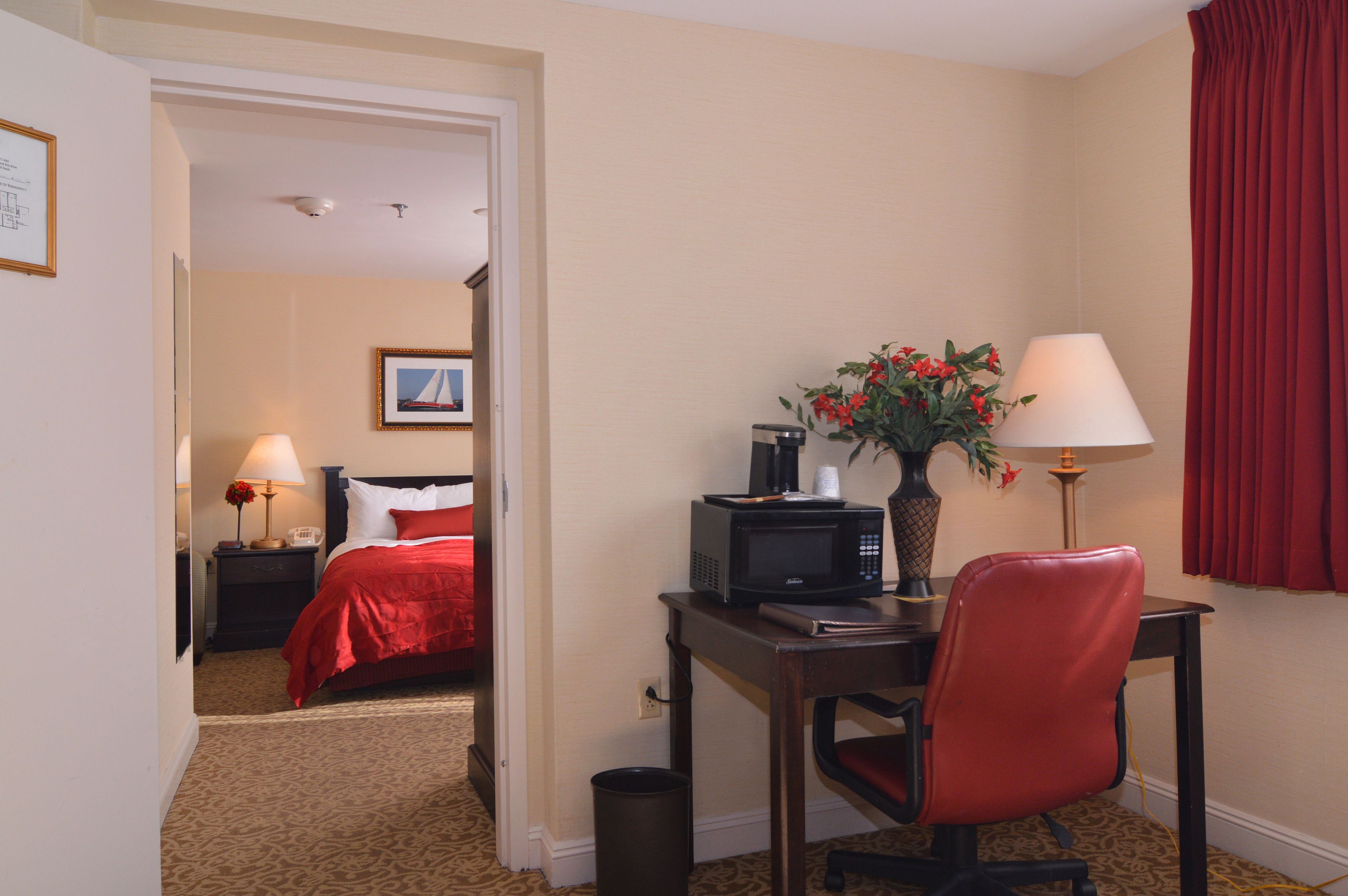 Une chambre d’hôtel comprenant un lit, un bureau avec un ordinateur, une chaise, une poubelle et une lampe.