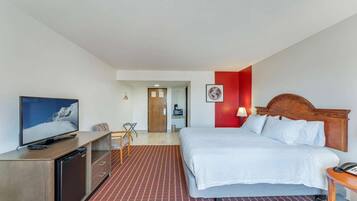 Una habitación de hotel con cama, televisión, escritorio y una pared de acento roja.