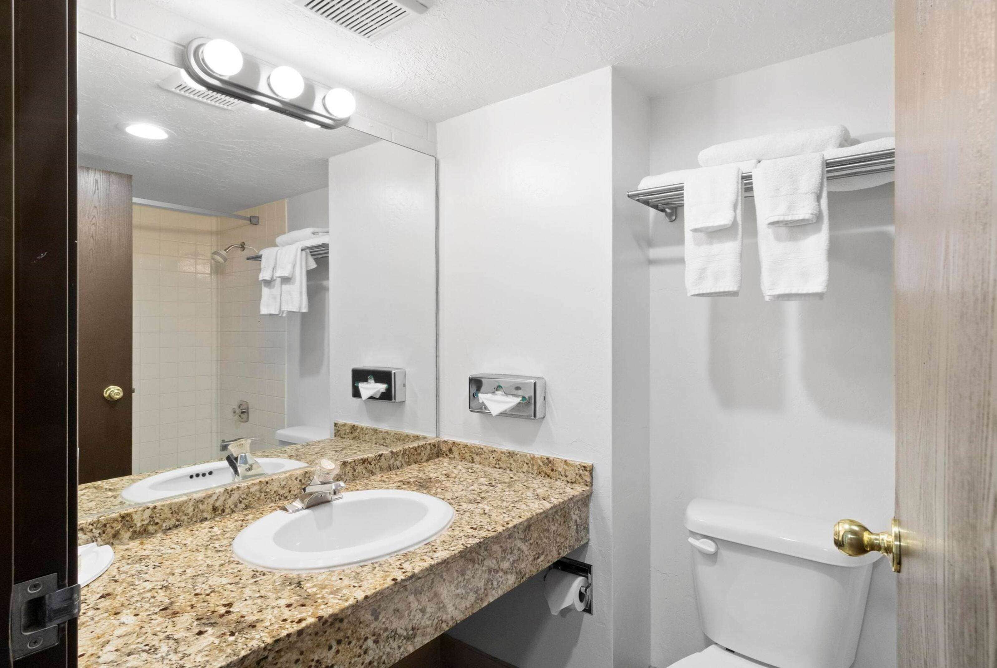 Een badkamer met twee wasbakken, een toilet, een handdoekhouder en een spiegel.