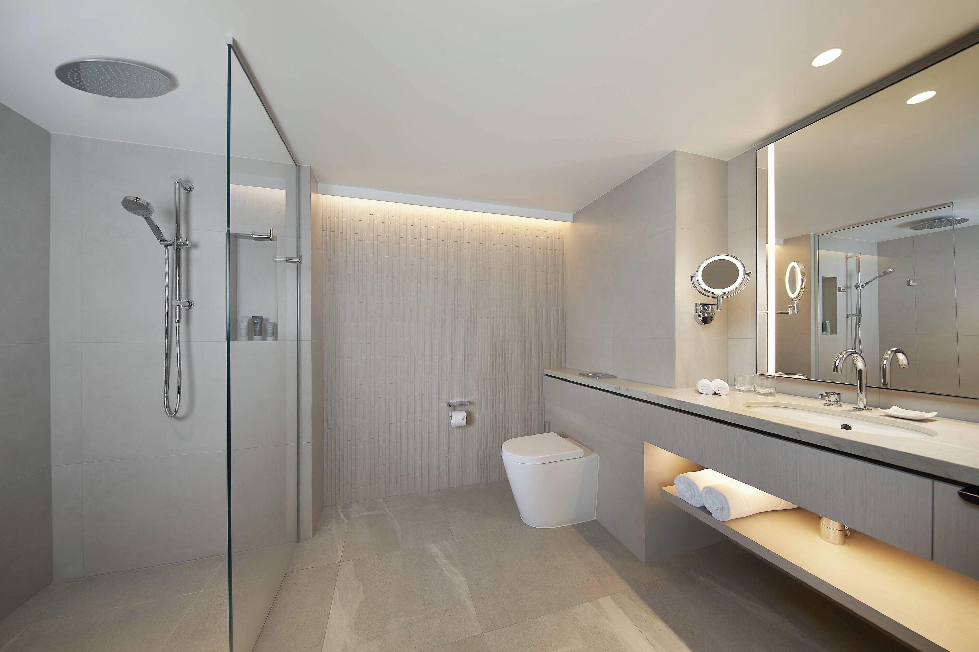 A modern bathroom with a glass-enclosed shower, a large mirror, and a vanity with a countertop.