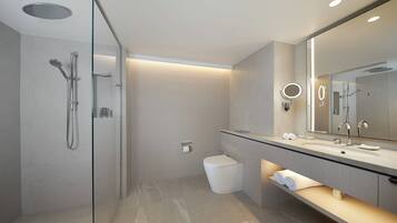 A modern bathroom with a glass-enclosed shower, a large mirror, and a vanity with a countertop.
