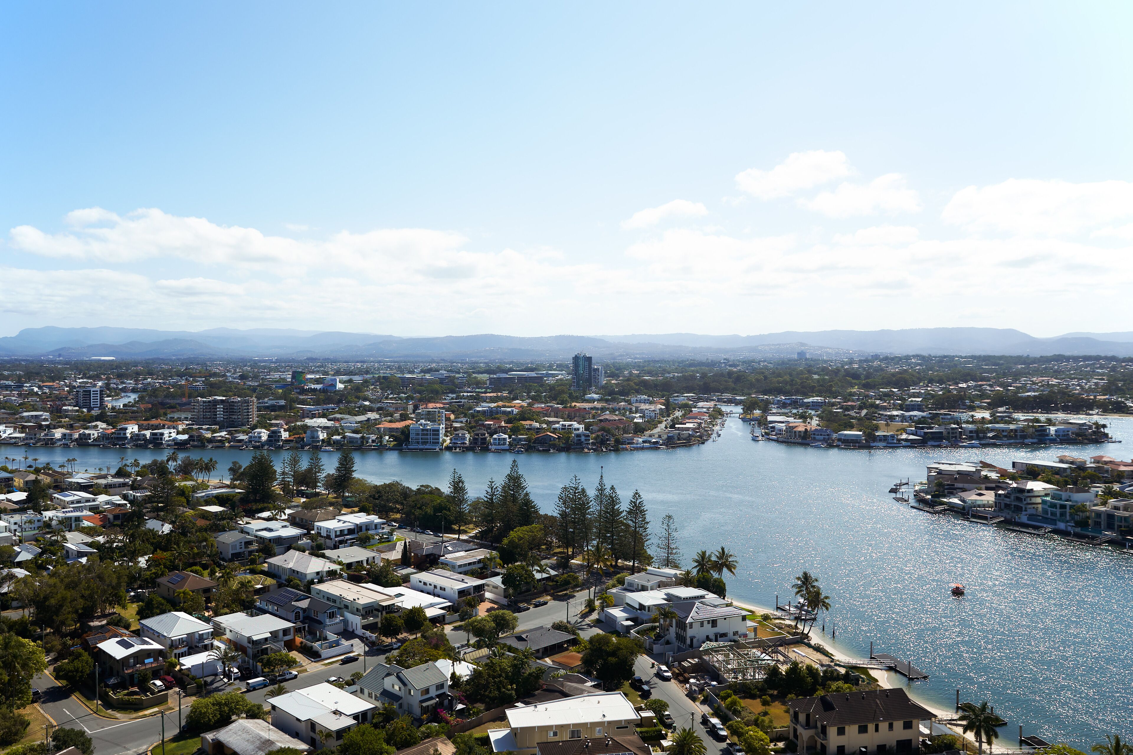 A coastal cityscape with residential buildings, a marina, and a clear view of the water.