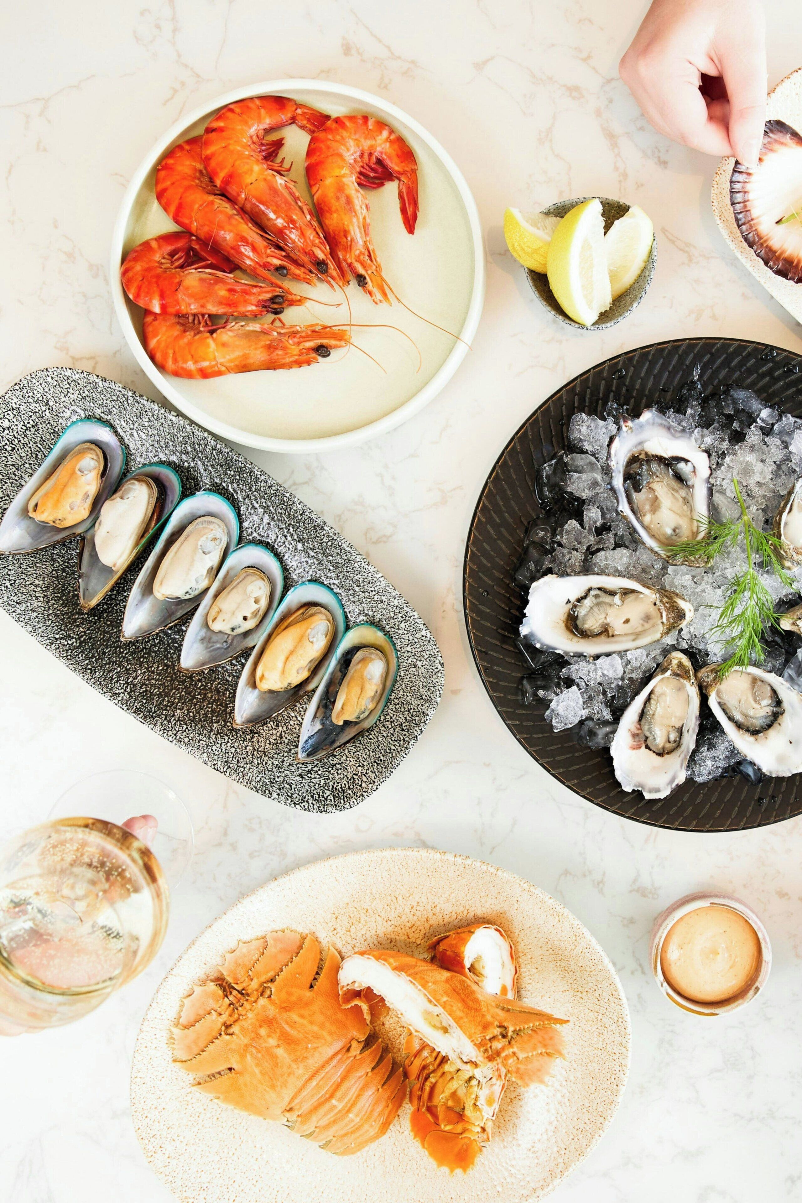 A seafood platter with shrimp, oysters, and lobster on a marble table.