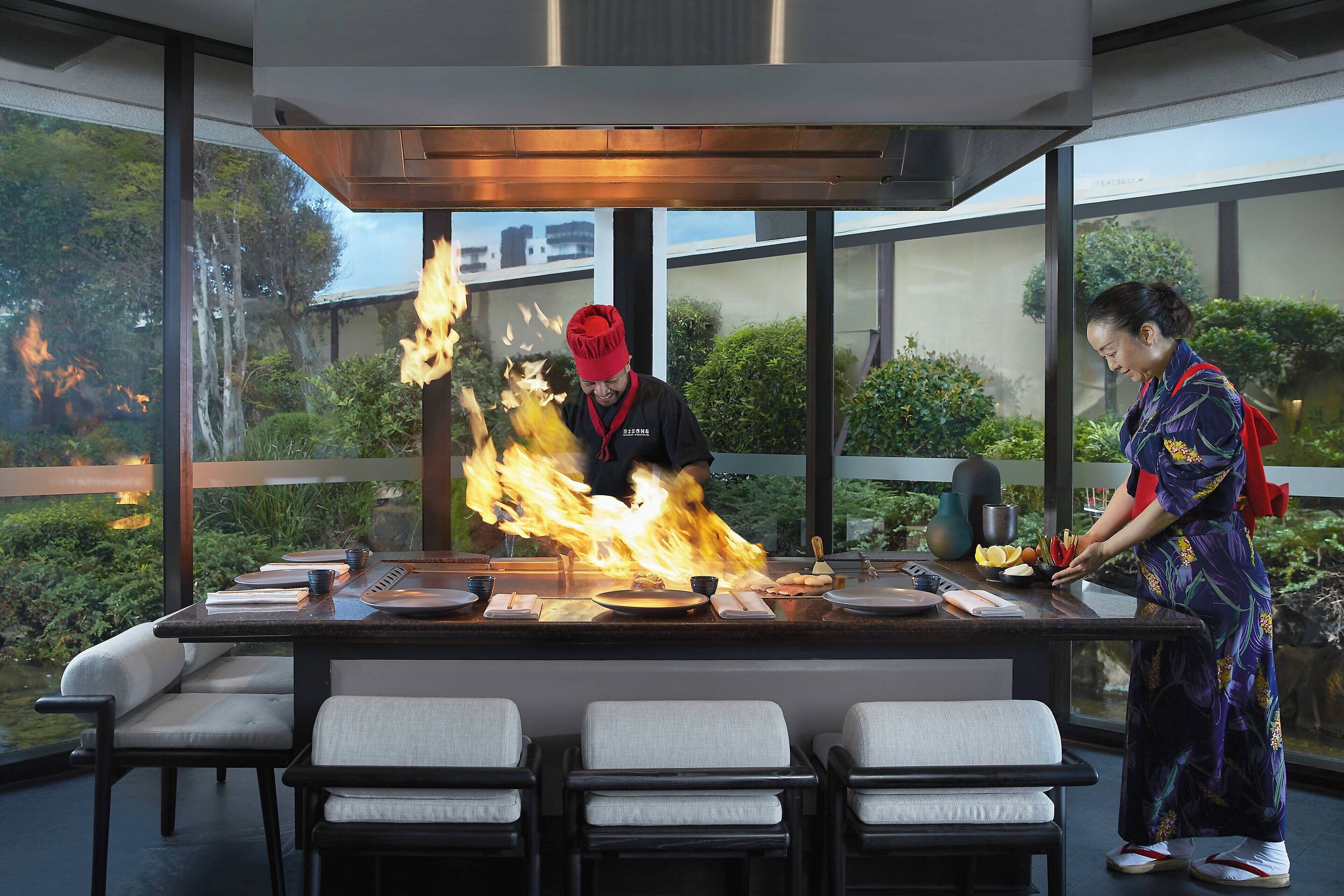 A modern kitchen with a chef performing a flambé.