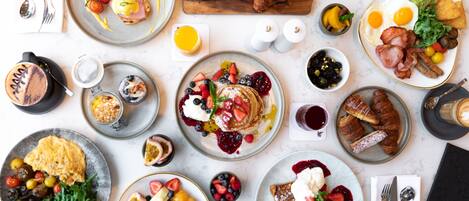 A breakfast buffet with various dishes including eggs, pastries, and fruit.