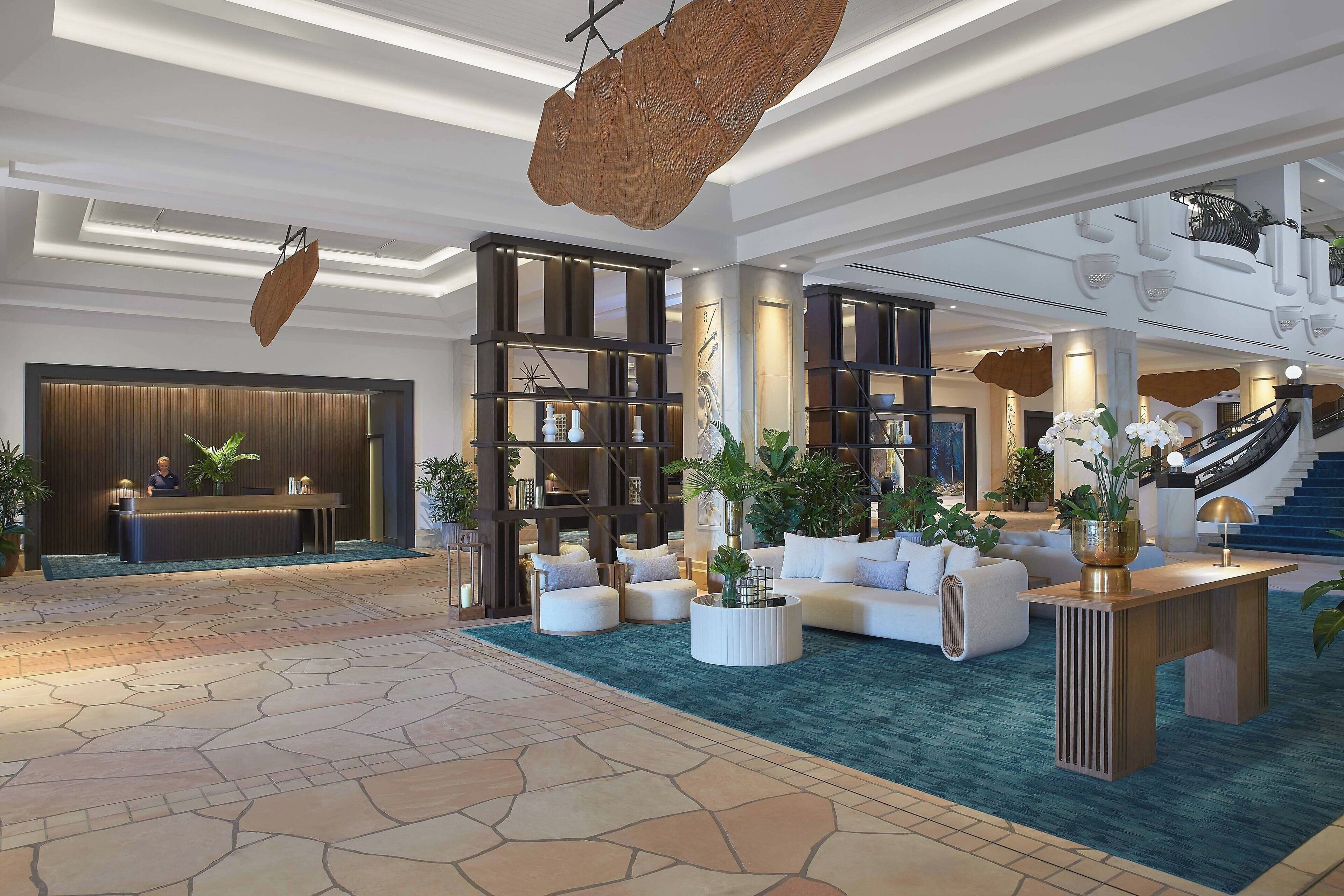 A spacious lobby with a reception desk, seating area, and staircase.
