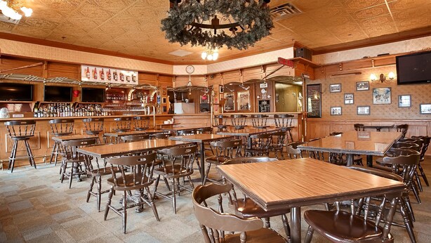 Un bar avec des meubles en bois et une grande variété de bouteilles. Les murs sont ornés d’horloges et de tableaux encadrés.