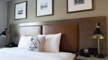 A hotel room with a large bed, two bedside lamps, a nightstand with a phone, and three framed pictures on the wall.