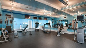 Une salle de sport équipée de matériel d’exercice, d’un distributeur d’eau et d’un miroir.