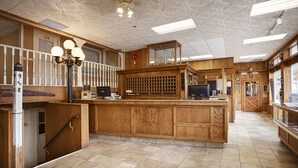 Un comptoir d’accueil en bois, équipé d’un ordinateur, d’une caisse enregistreuse et d’une enseigne indiquant « Trading St. ».