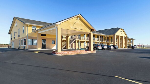 A two-story motel with a covered parking area and multiple cars parked.