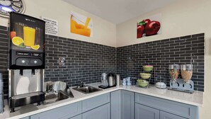 Una cocina moderna con un dispensador de jugo, un lavamanos y varios electrodomésticos.