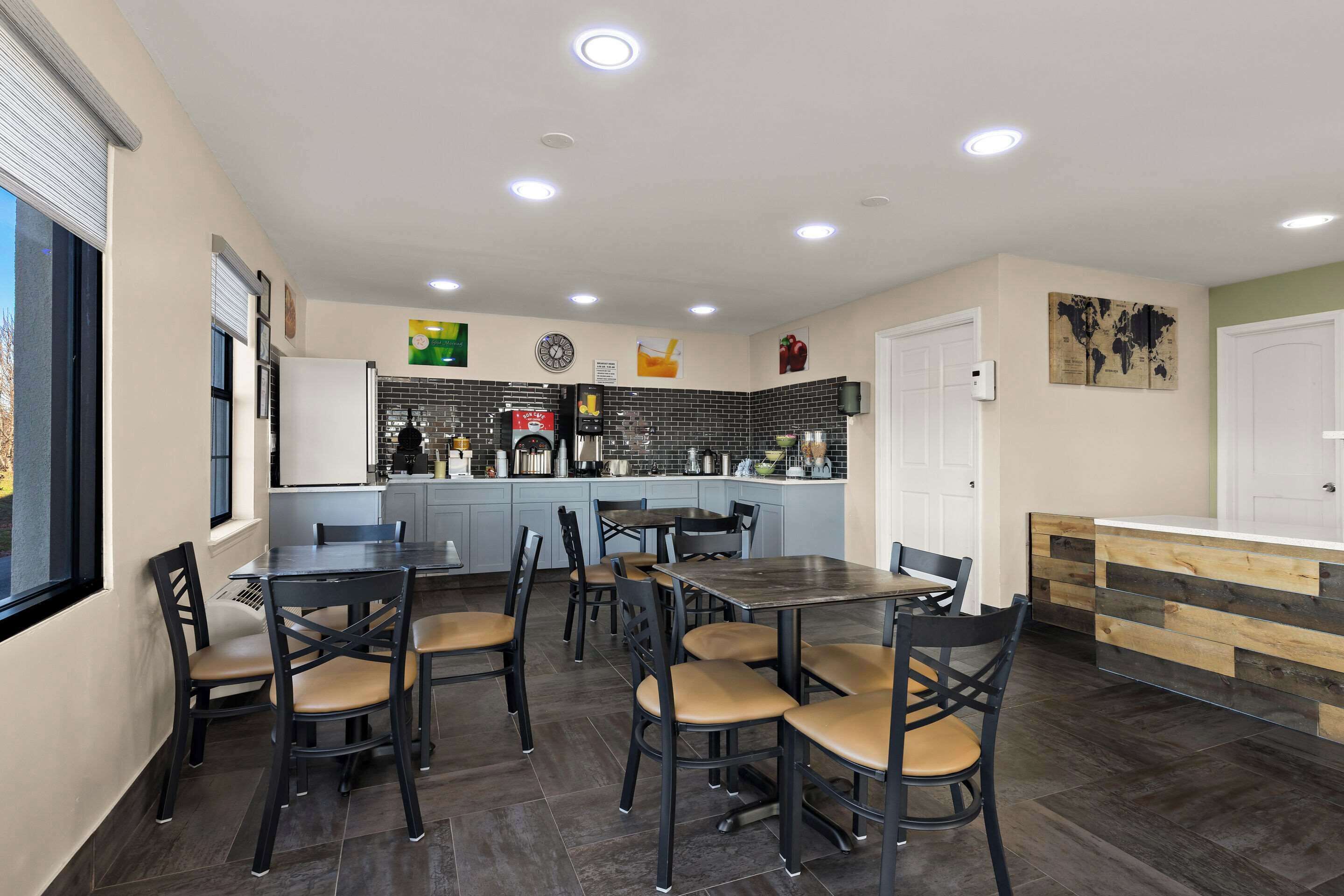 Una cocina moderna con una isla central, comedor con sillas y vistas al exterior.