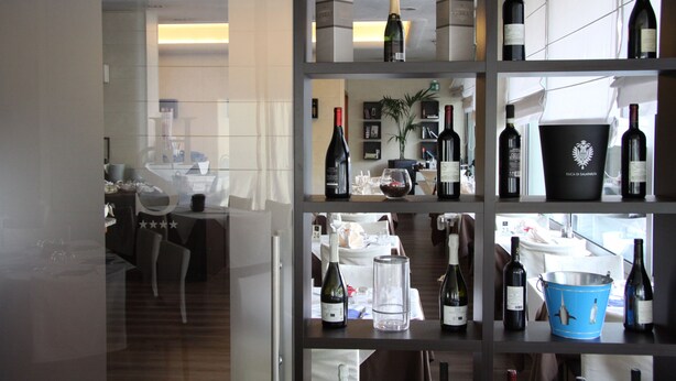 A wine cellar with shelves displaying various bottles and a bucket. - LH Hotel Sirio Venice (Mestre)