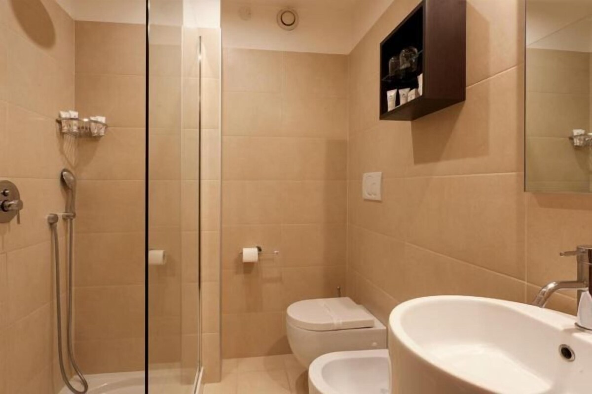 A bathroom with a glass shower enclosure, a toilet, and a sink.
