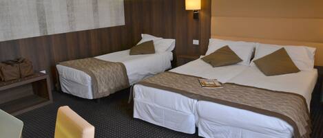 A hotel room with two single beds, a desk, and a chair.