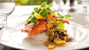 A plate of food with salmon, rice, and vegetables.