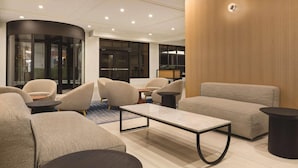 A modern hotel lobby with a curved wall, seating area, and a wooden accent wall. - Radisson Hotel Seattle Airport (SeaTac)