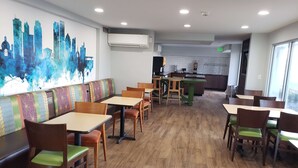 A restaurant with wooden flooring, green cushioned chairs, and a cityscape mural on the wall. - Wingate by Wyndham Dayton North (Dayton)