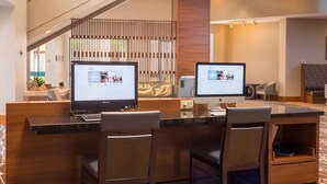 A hotel reception area with a curved desk, two computer monitors, and a seating area with chairs. - Hilton Phoenix Airport (Phoenix)