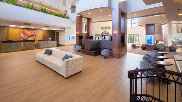 A spacious lobby with a reception desk, seating area, and a staircase leading to an upper level. - Hilton Phoenix Airport (Phoenix)