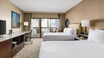 A hotel room with two beds, a desk, a chair, a television, and a window with curtains.