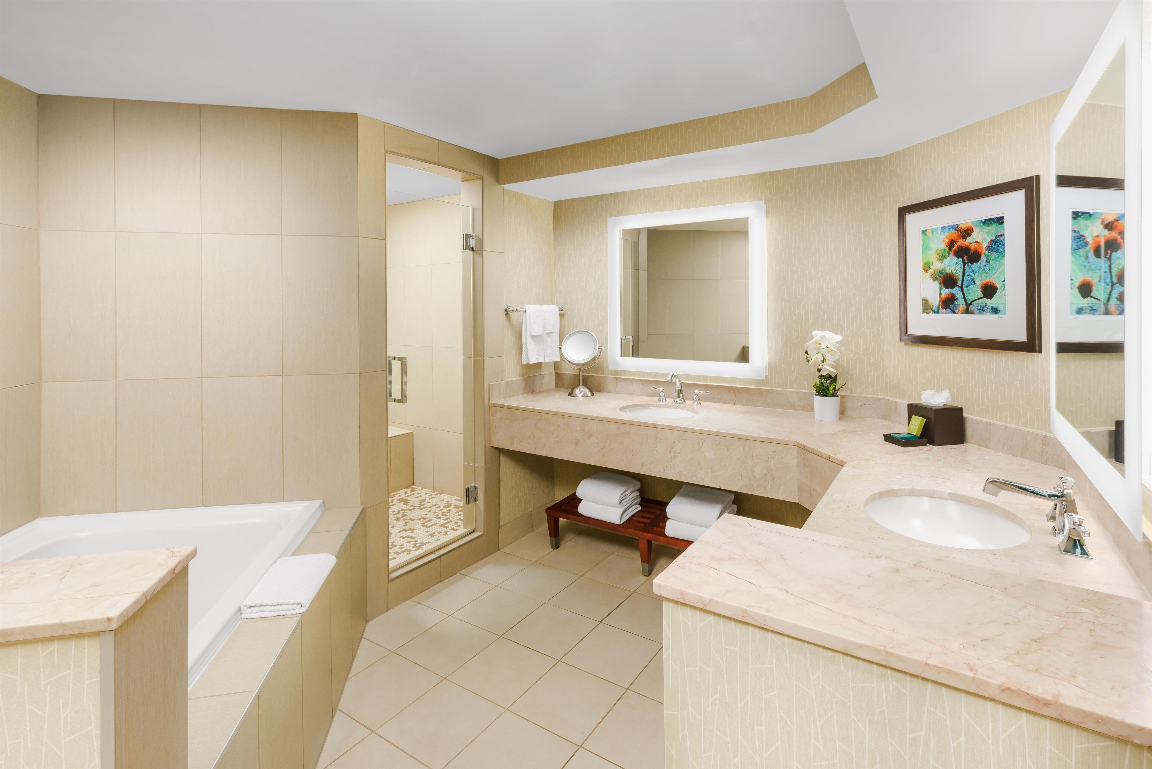 Un baño moderno con bañera, dos lavamanos, un espejo grande y ducha.