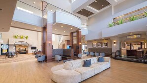 A spacious lobby with a central seating area, a staircase, and a coffee shop. - Hilton Phoenix Airport (Phoenix)