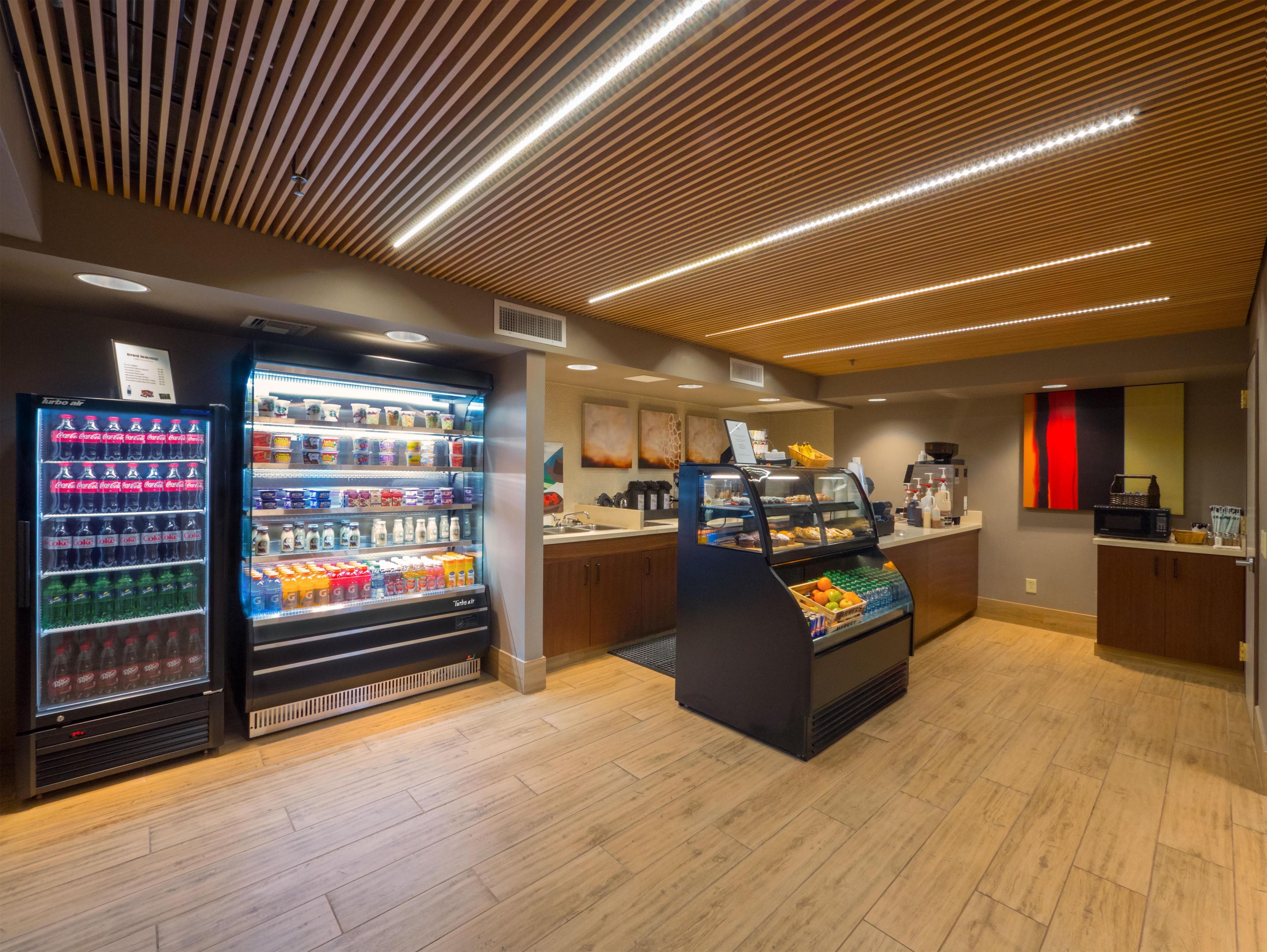 A modern food court with vending machines, a fruit display, and a coffee station.