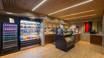 A modern food court with vending machines, a fruit display, and a coffee station.