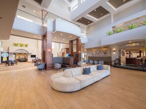 A spacious lobby with a high ceiling, seating areas, and a Starbucks coffee shop. - Hilton Phoenix Airport (Phoenix)
