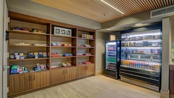 A clean, well-organized room with wooden shelving stocked with various items, a large beverage refrigerator, and a ceiling with a slatted design.