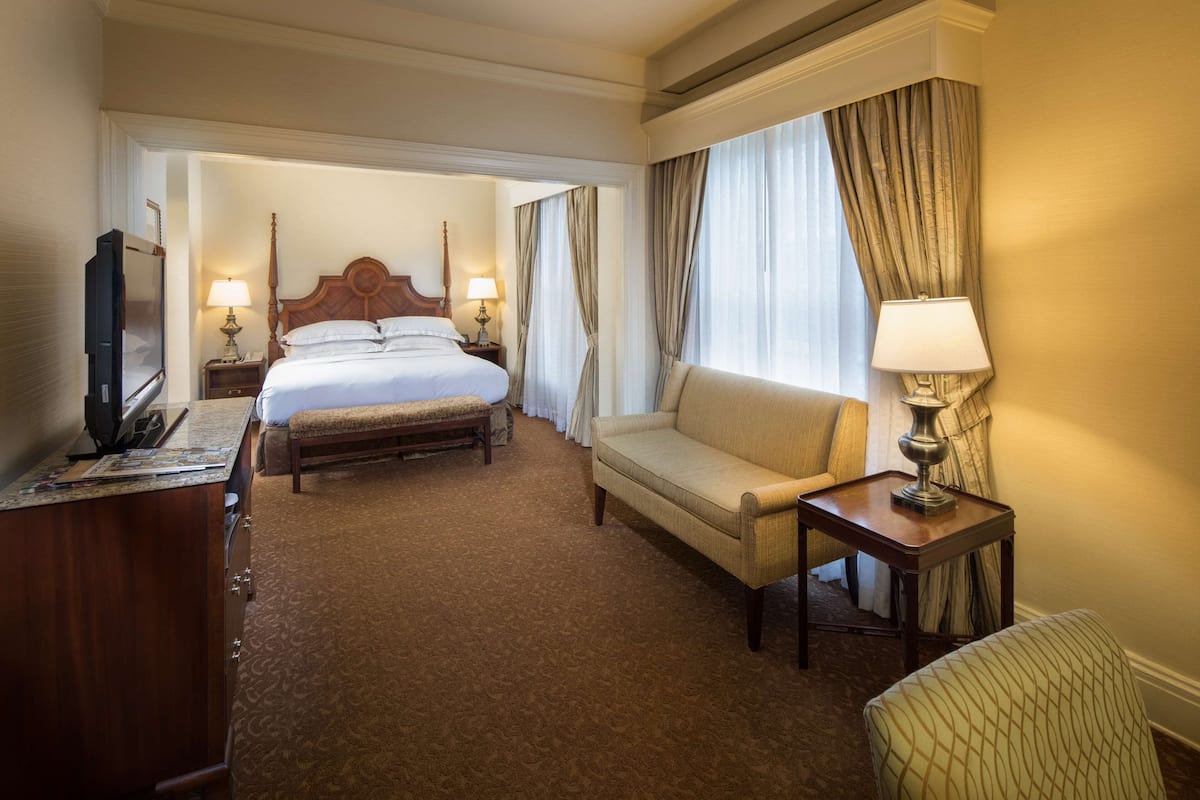 Ein Hotelzimmer mit Bett, einer Couch, einem Schreibtisch und einem Fernseher.