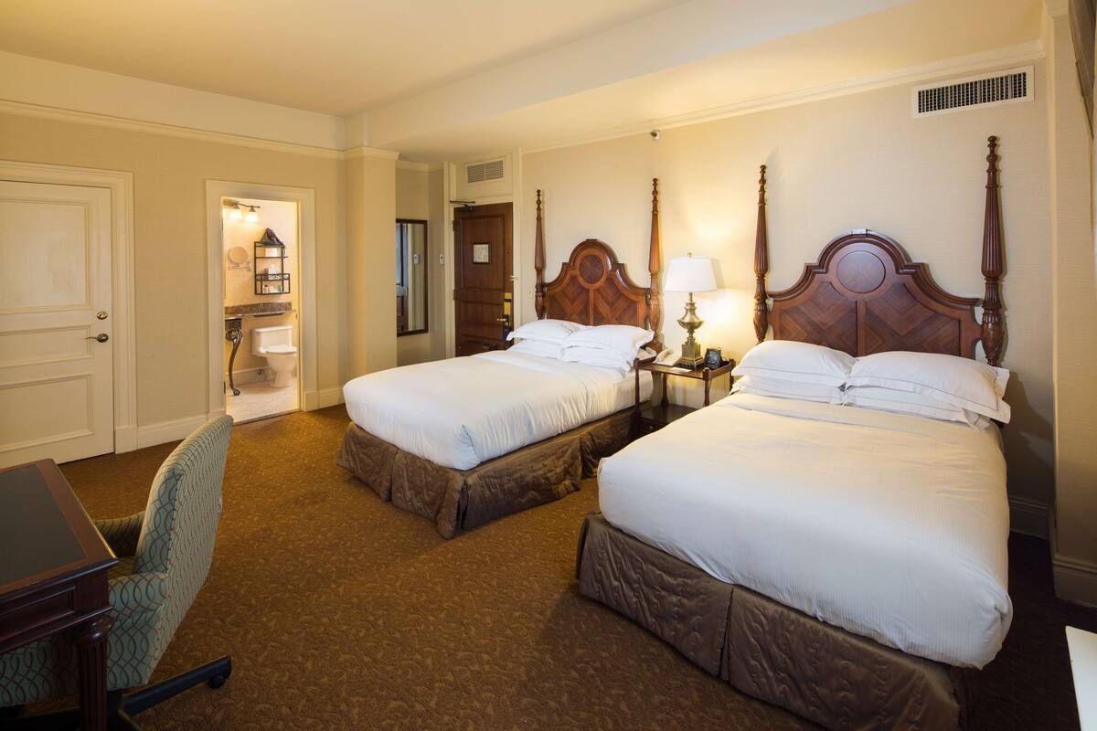 Ein Hotelzimmer mit zwei Betten, einem Schreibtisch und einem Stuhl.