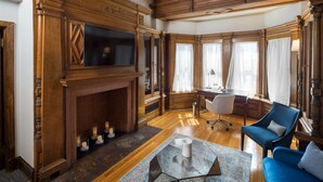 Un salon spacieux avec une cheminée, des boiseries, un téléviseur et un canapé bleu.