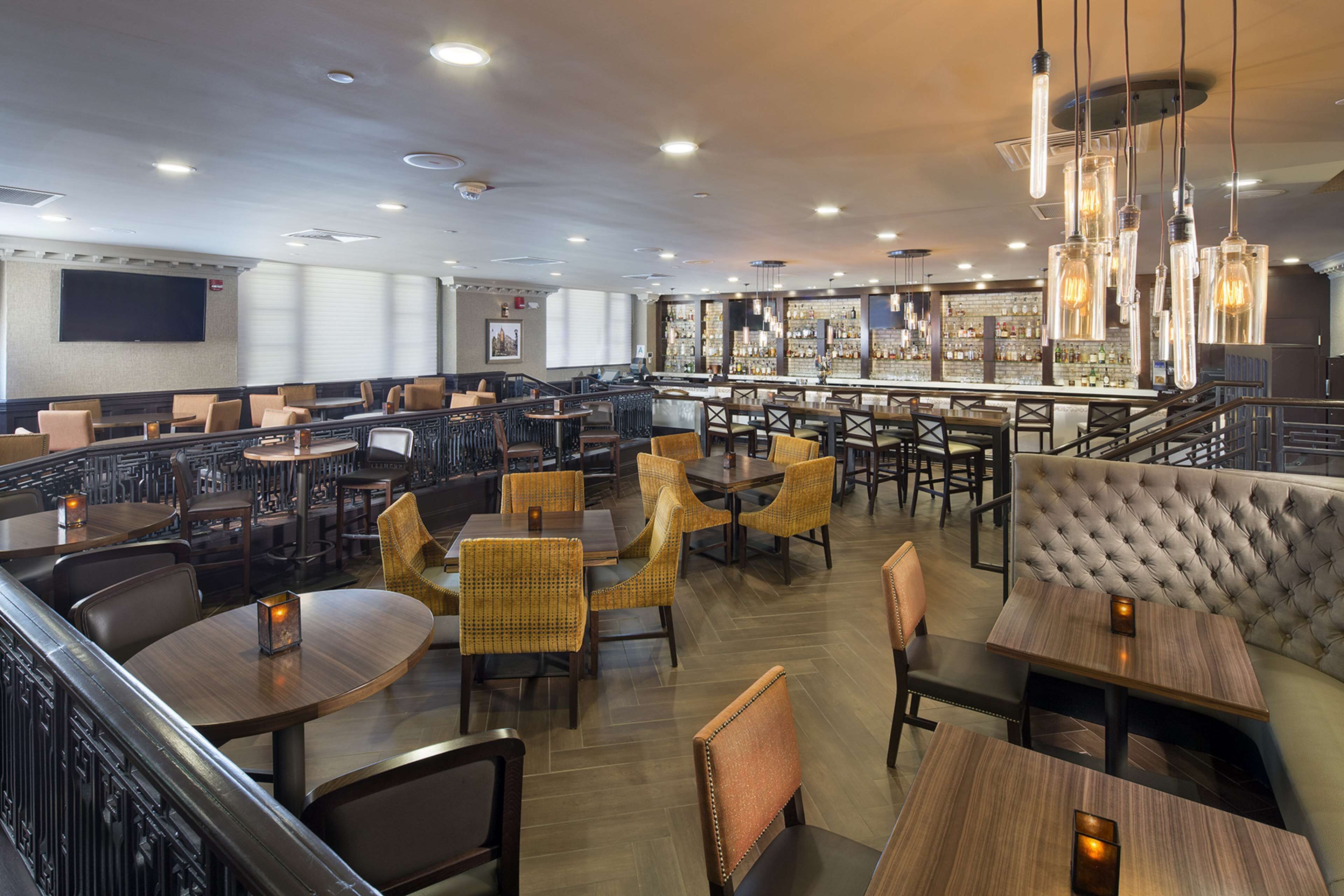 A restaurant with multiple seating areas, including booths and tables, and a bar with a variety of bottles.