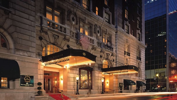 Un hôtel historique à l’architecture somptueuse, doté d’une entrée imposante et d’un tapis rouge menant aux portes.