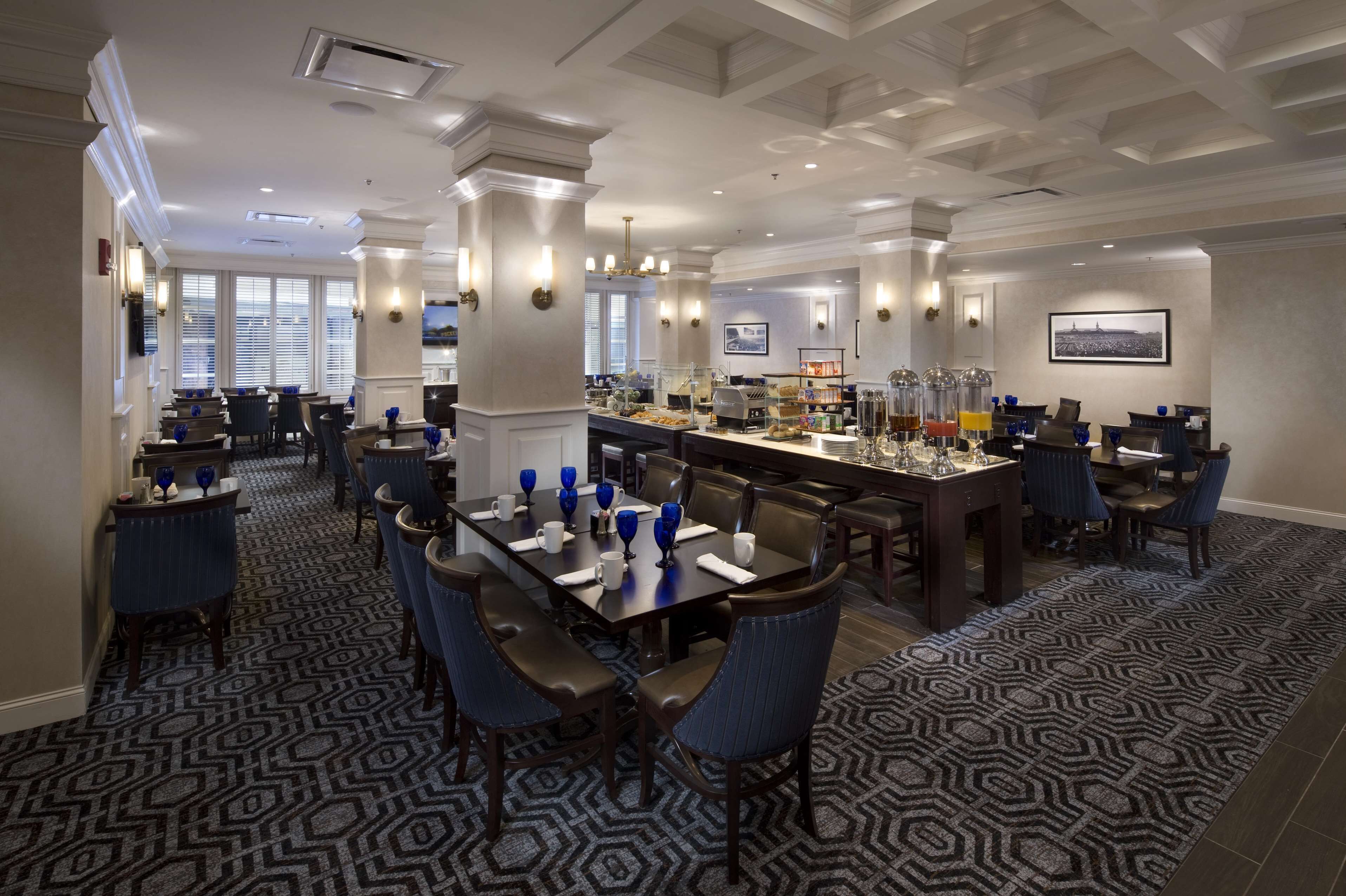 A hotel dining area with multiple tables, chairs, and a bar.