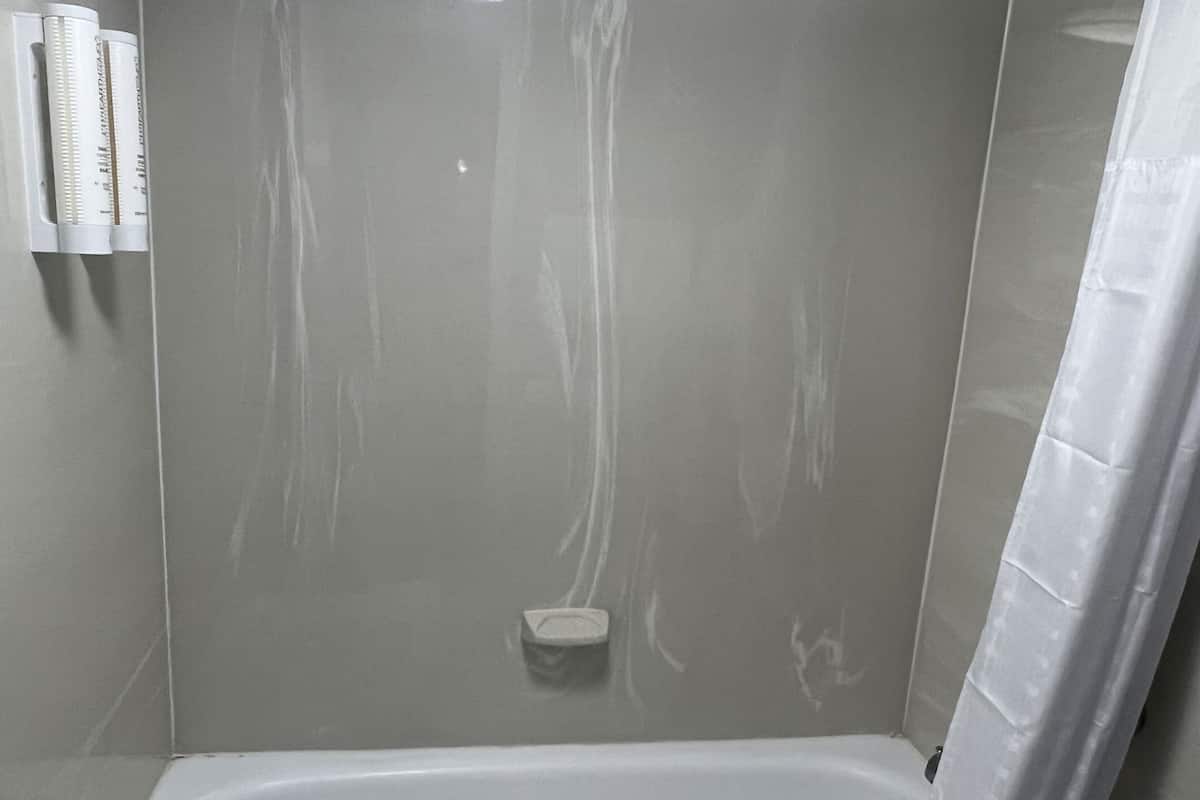A bathroom with a bathtub, a shower, and a toilet. There are two white bottles on the wall.