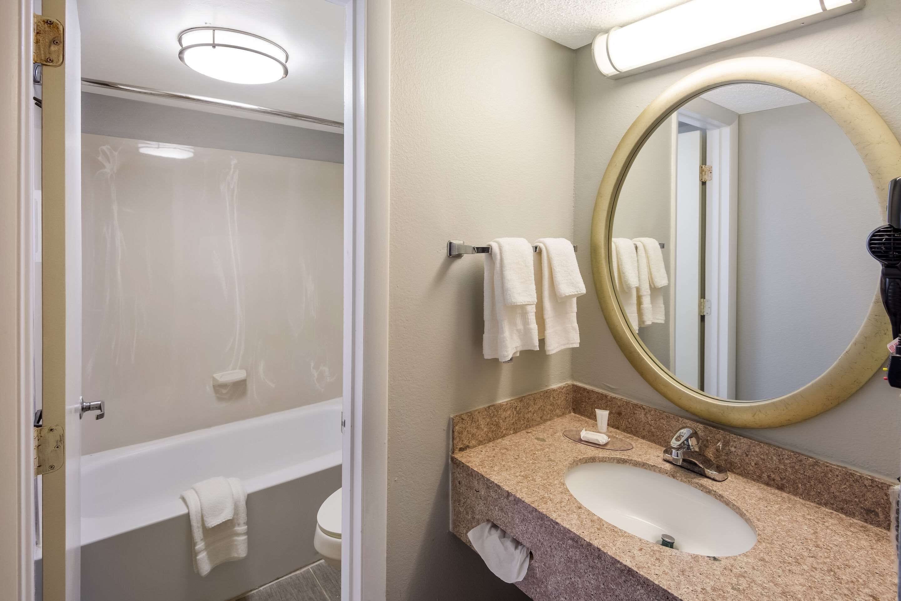 A bathroom with a bathtub, a sink, and a mirror.