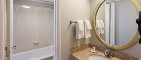 A bathroom with a bathtub, a sink, and a mirror.