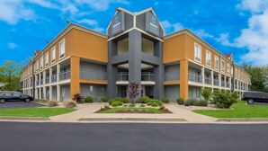A multi-story hotel with a central atrium, balconies, and a parking lot. - Clarion Pointe Indianapolis Northeast (Indianapolis)