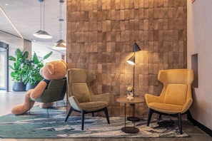 Un vestíbulo con dos sillones, una lámpara de pie y una planta en maceta.