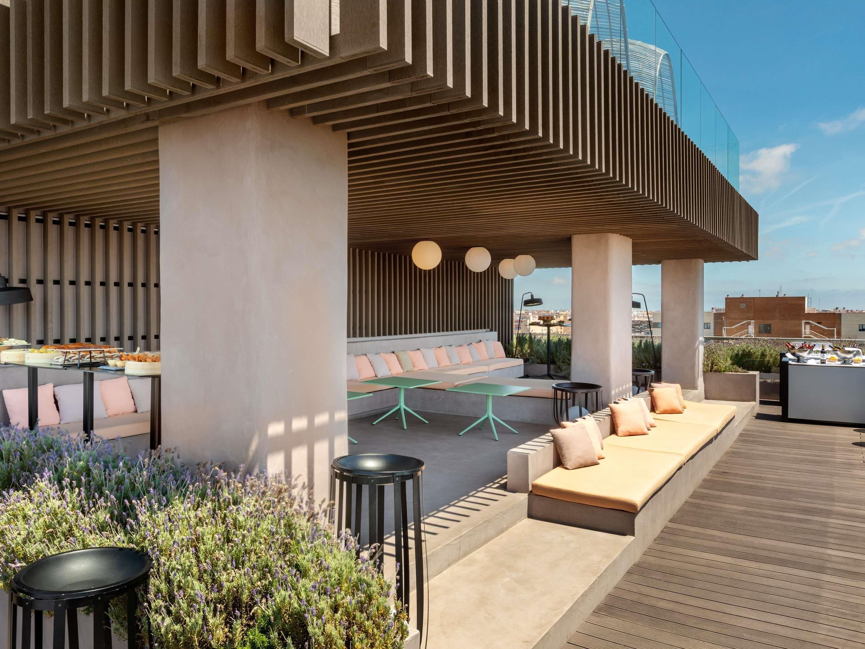 Um lounge no terraço com área externa para sentar, buffet e vista para a cidade.