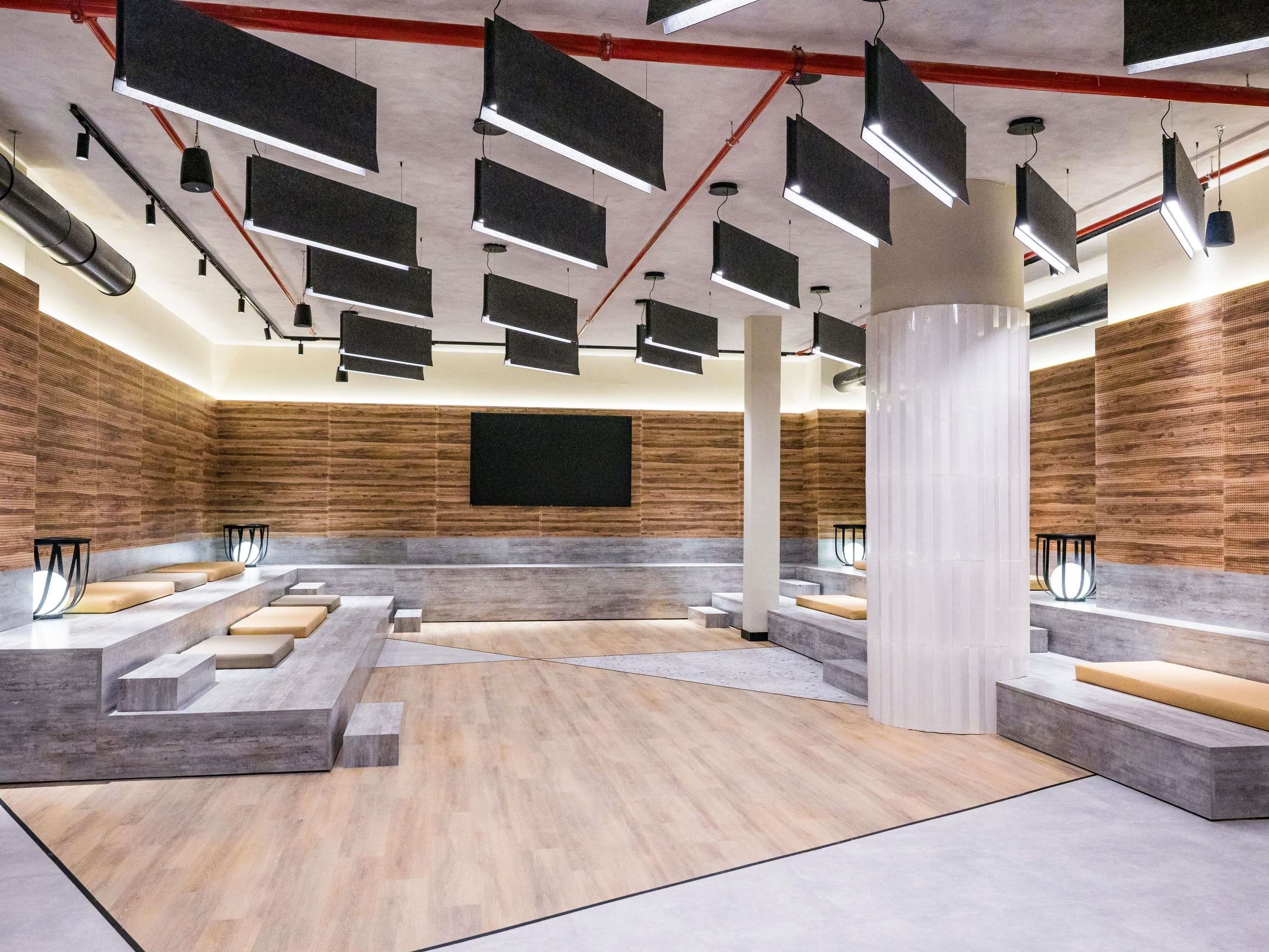 Un interior moderno con asientos escalonados, una pantalla grande e iluminación industrial.