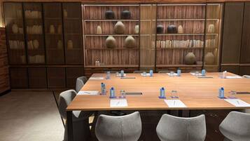 Una sala de conferencias con una larga mesa, sillas grises y estantes con adornos.